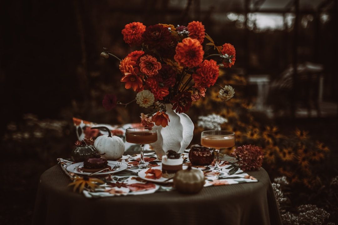 Ett vackert dukat kakbord utomhus med bakverk, blommor och drinkar.